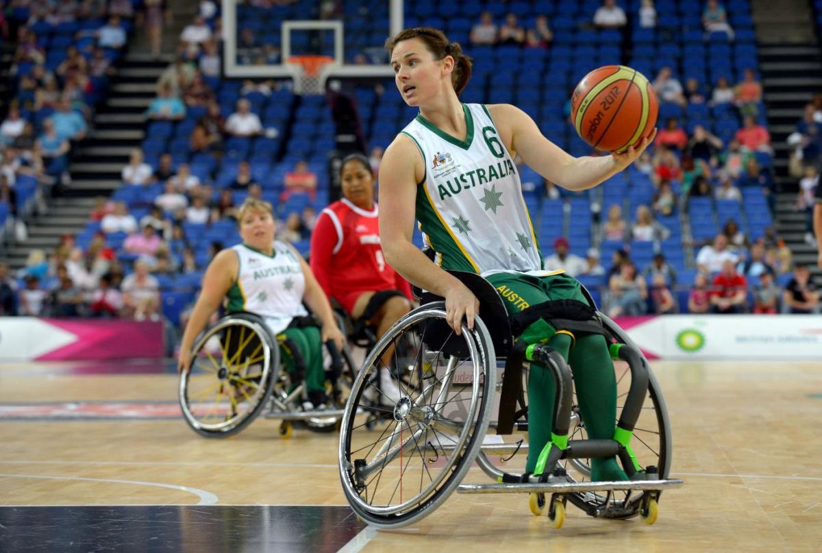 A female wheelchair basketball player is dribbling the ball during a game